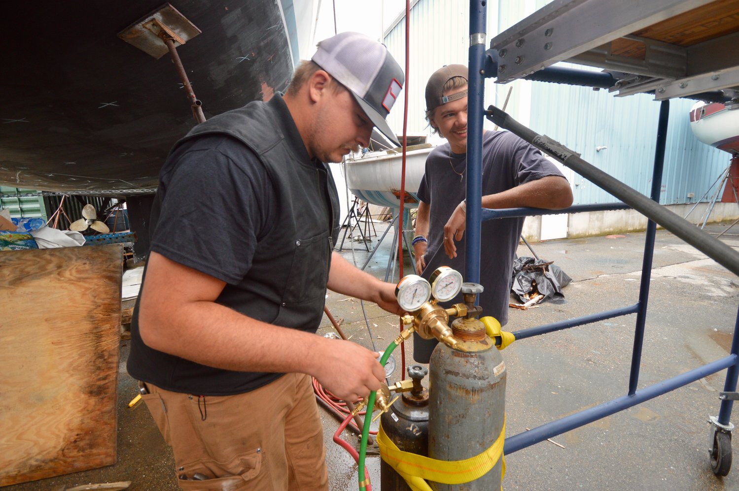 Jasper Fields (left) and Levi Deane Thorson are among of the volunteers getting the boat into shape at Hinckley. Jasper is the son of the boat’s owner, Ty Fields, while Levi is a member of YWAM who will be among the crew members headed to Micronesia.
