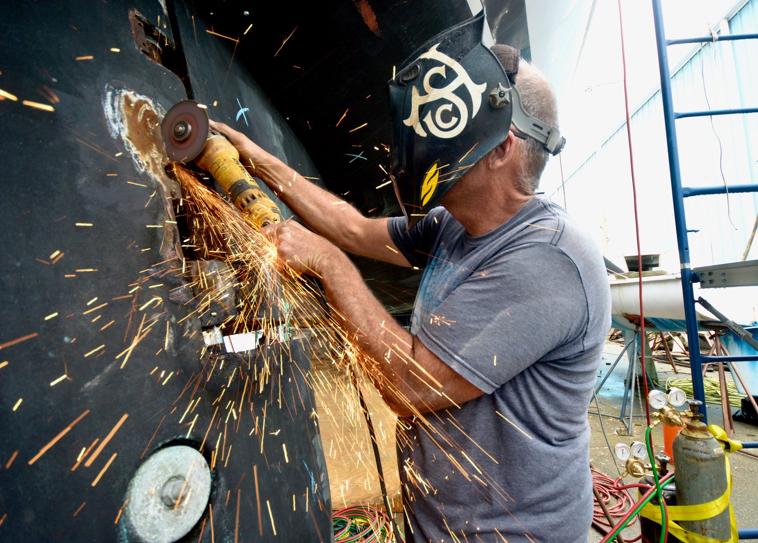 Sparks fly as owner Ty Fields cuts along one of Pacific Star’s rudders that needed to be dropped during restoration work at Hinckley Boat Yard last week.