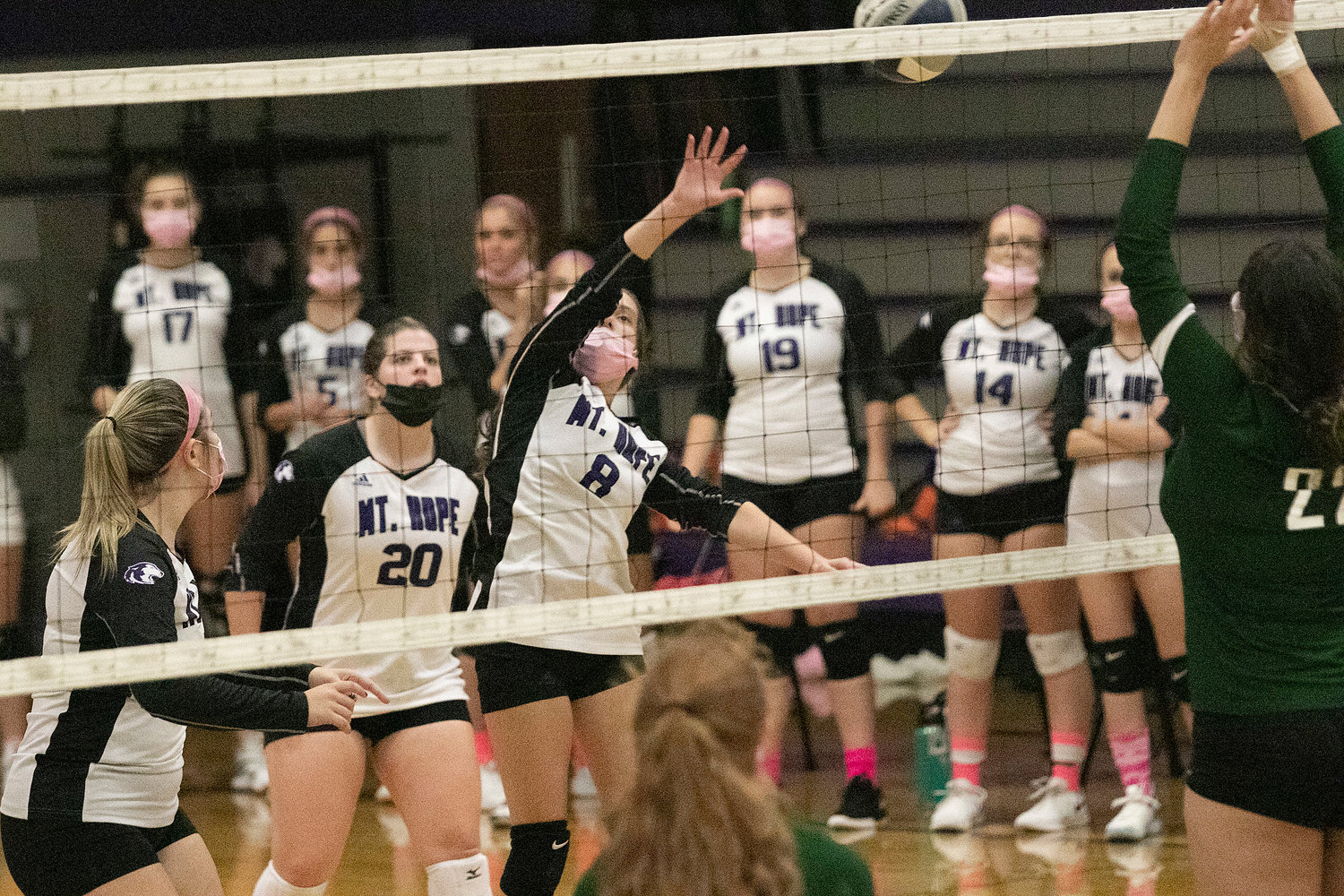 Mia Padula (left), Grace Stephenson look on as teammate Emma Torres hits the ball over the net. 