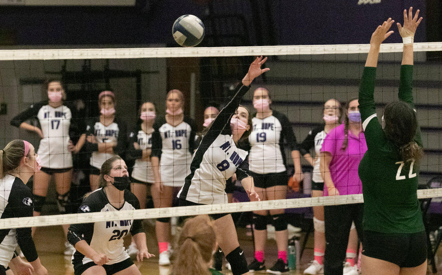 Mia Padula (left), Grace Stephenson look on as teammate Emma Torres hits the ball over the net. 