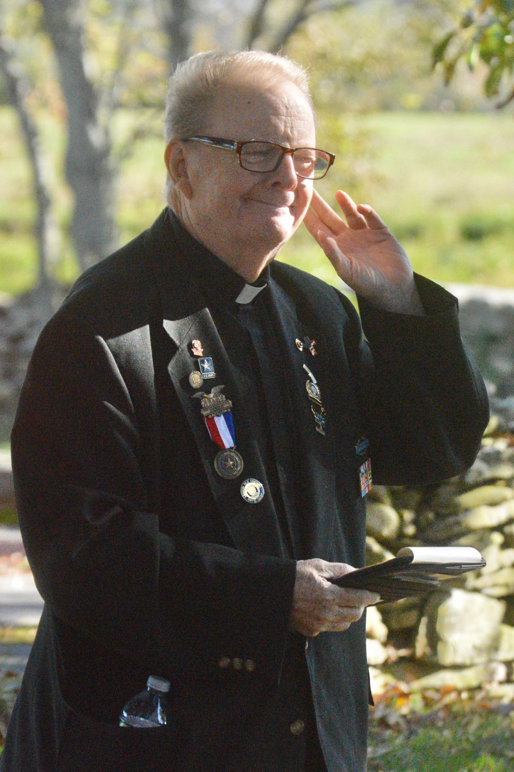 The Rev. Philip G. Salois cups his ear as a plane flies overhead before his invocation. “Who arranged for the flyby?” joked Father Salois, a Vietnam veteran who gave the opening prayer in the U.S. House of Representatives in February 2019.