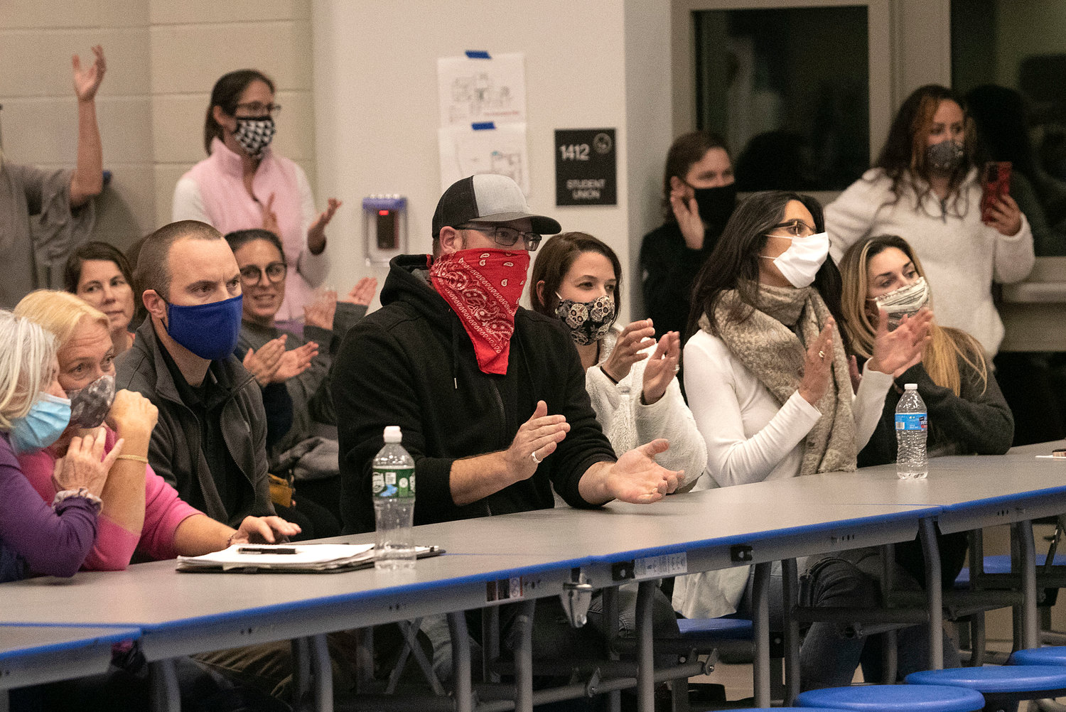 Members of the audience cheer after listening to a teacher speak during Thursday night's pre-termination hearing. The committee voted 3-1 to fire three unvaccinated teachers.