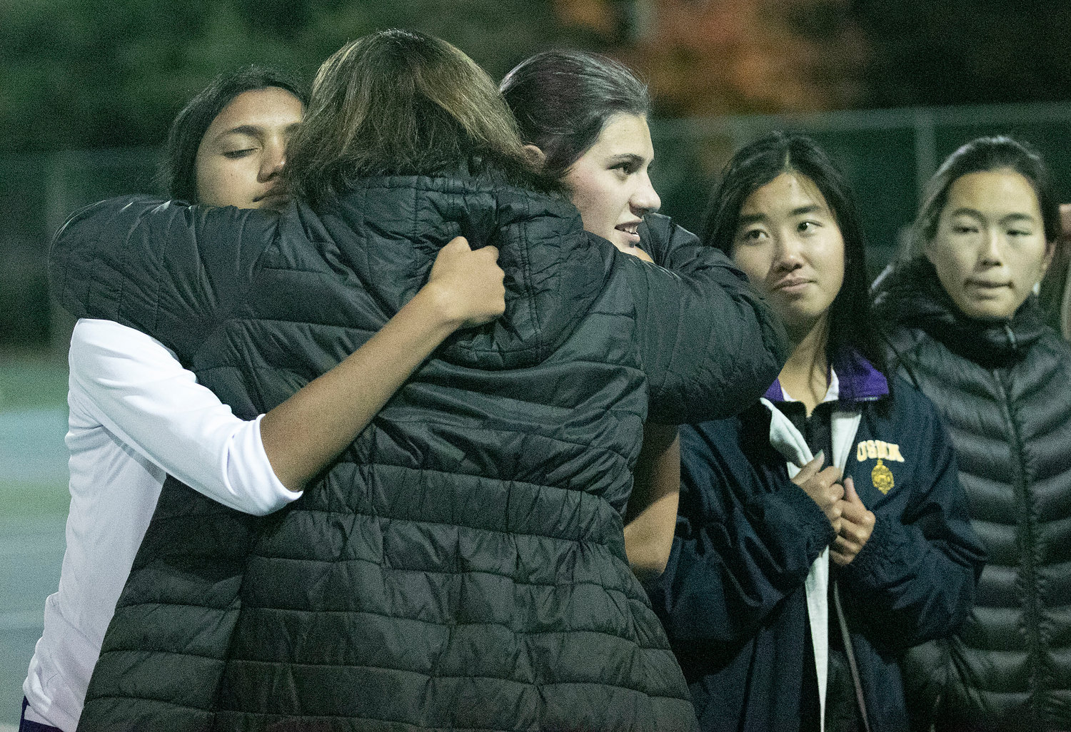 Aditi Mehta (left) and Emily Marino get a hug from assistant coach Maureen Gauthier as Eva White looks on after the match. 