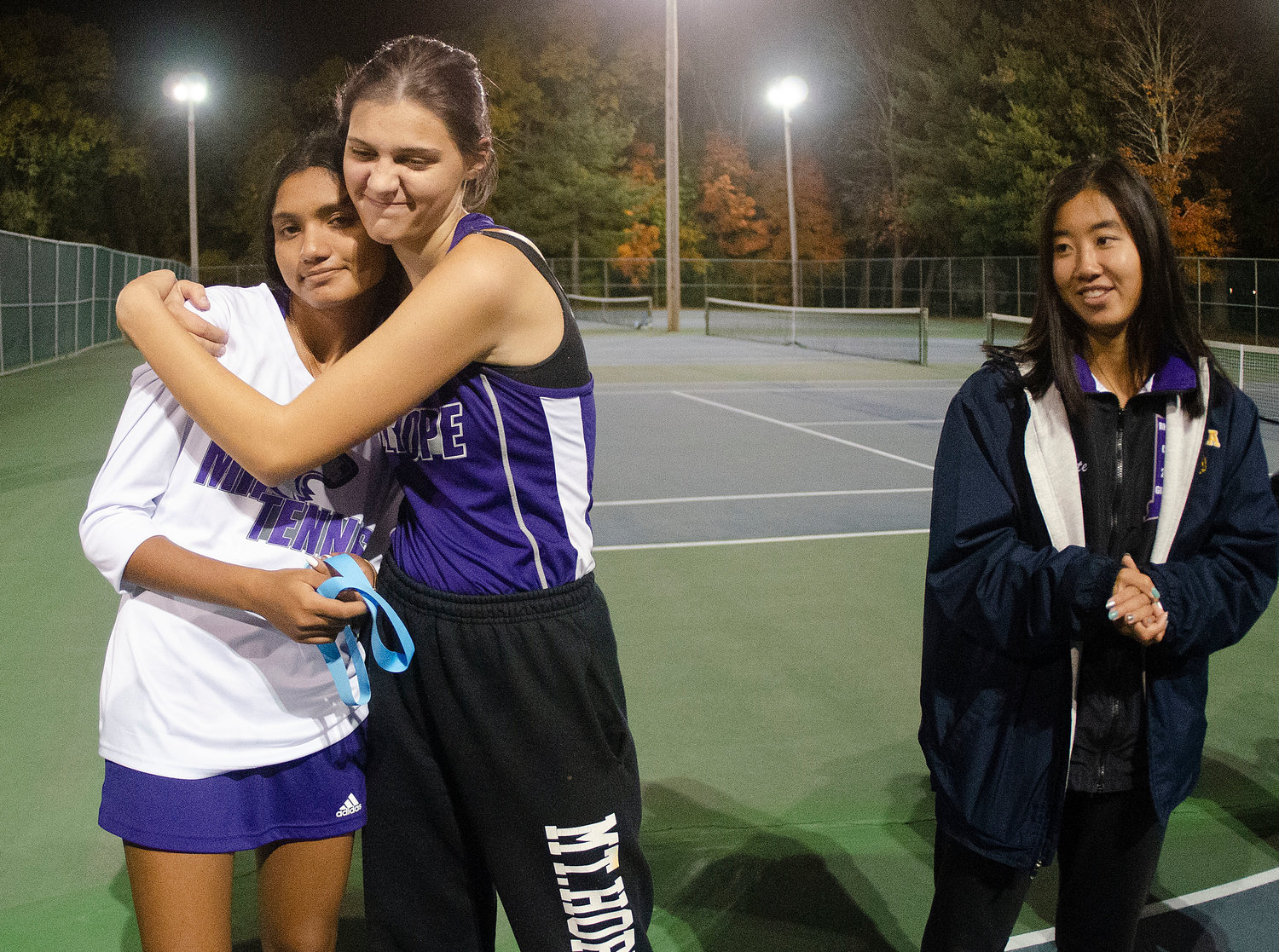 Aditi Mehta (left) gets a hug from her doubles partner, Emily Marino as Eva White looks on after the match.