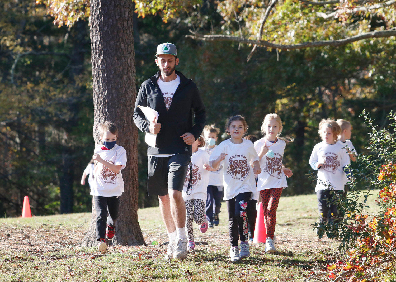Coach Ryan Kirby runs with a group cross county training behind the Elementary School on Monday. 