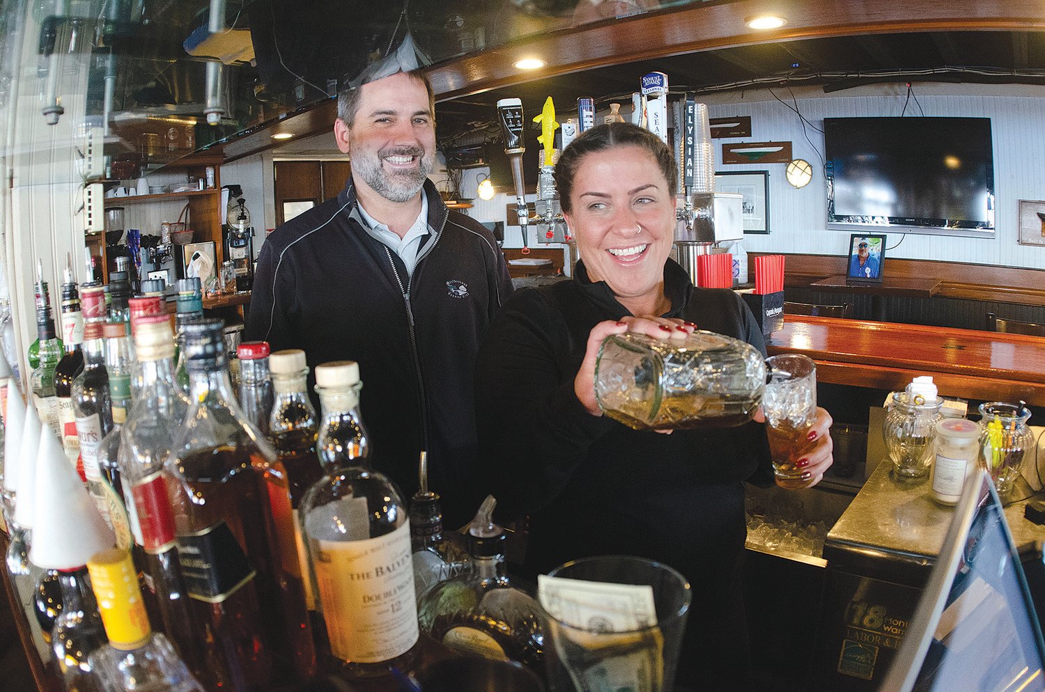Thames Waterside Grille manager Ben Wachter looks on as bartender Jaime Kuehl pours a drink for a customer during lunch on Friday. Wachter said this summer was “chaotic,” and he thinks the entire industry is facing an inflection point as low-wage workers leave and don’t look back.