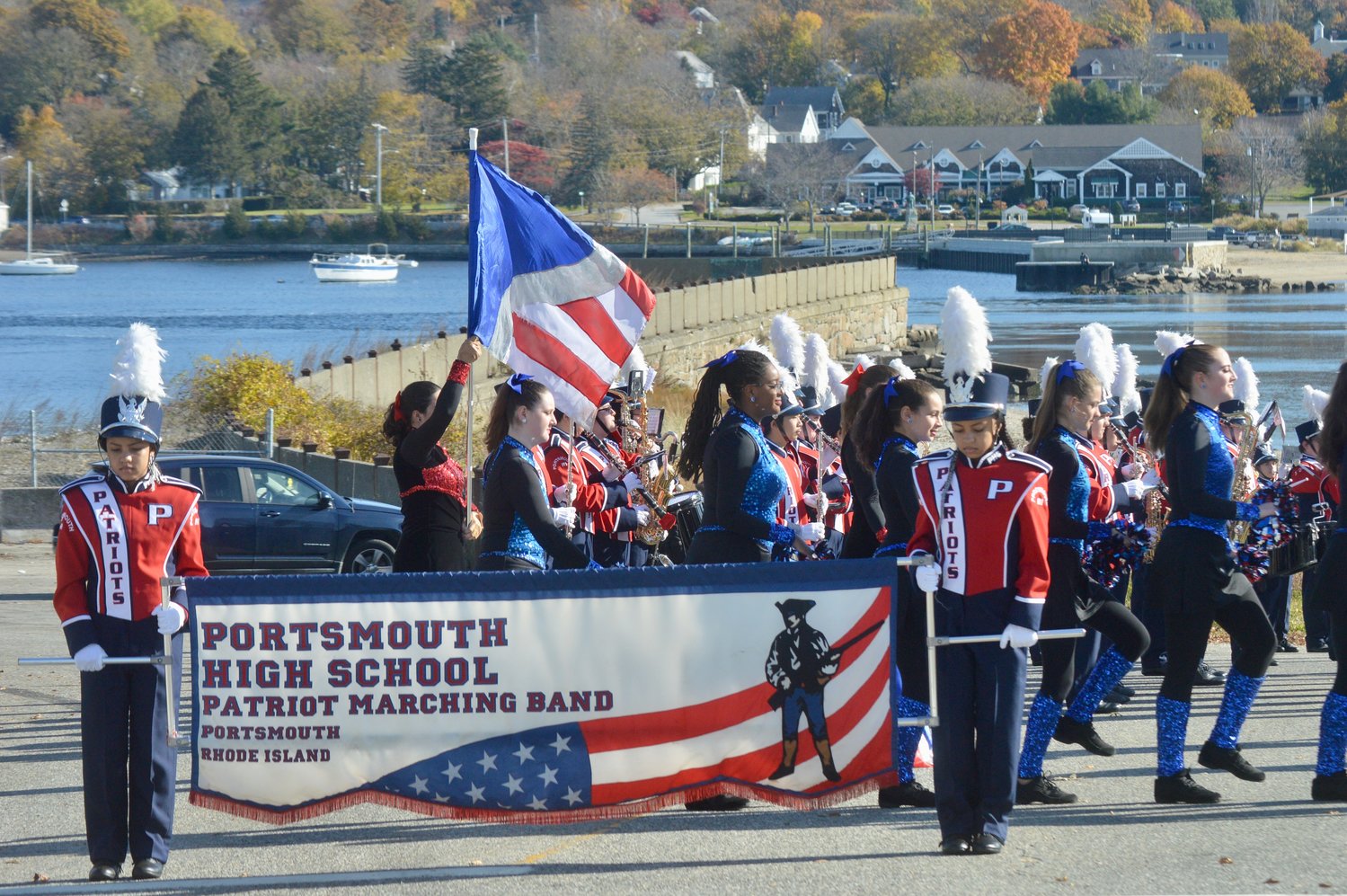 The PHS Marching Band warms up before the parade, with the Stone Bridge abutment and Teddy’s Beach in the background. Identical twins and PHS sophomores Makayla (left) and Keira Boxell are holding the banner.