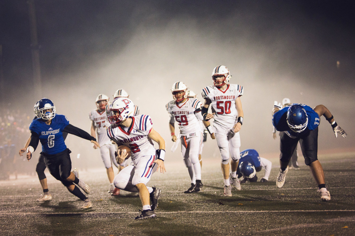 Patriots quarterback Benny Hurd carries the ball as the fog envelopes Portsmouth and Cumberland players during the second round of the Division I playoffs on Friday. Portsmouth prevailed, 24-7, and will face North Kingstown in the semifinals at 3:30 p.m. Saturday, Nov. 20, at Cranston Stadium.