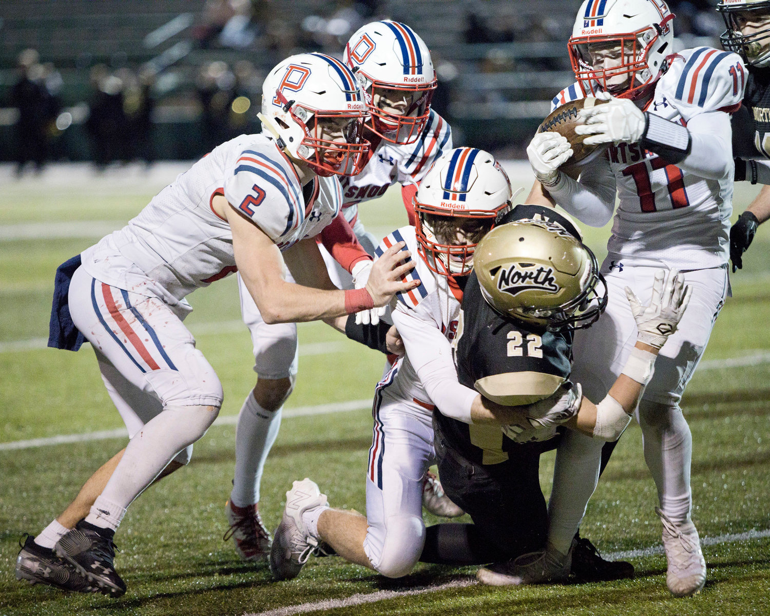 Gavin Bicho (right) attempts to pry the ball from a North Kingstown ball-carrier as his teammates make the tackle.