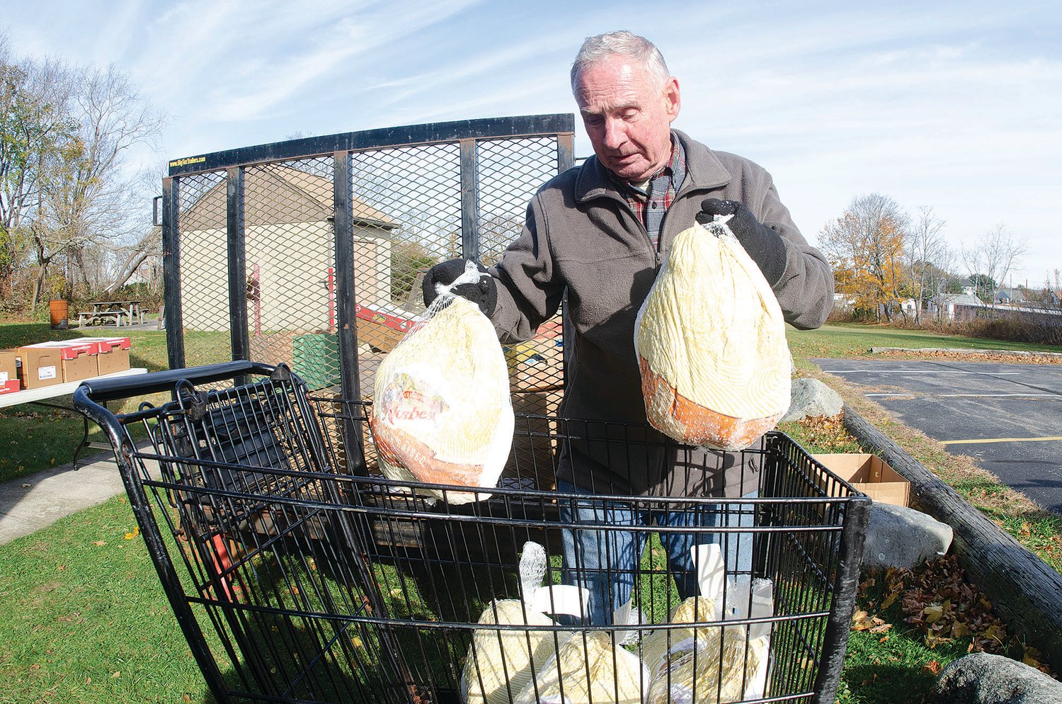 Portsmouth Community Food Bank volunteer Paul St. Laurent lifts two turkeys into a carriage while preparing an order for two families last Wednesday.
