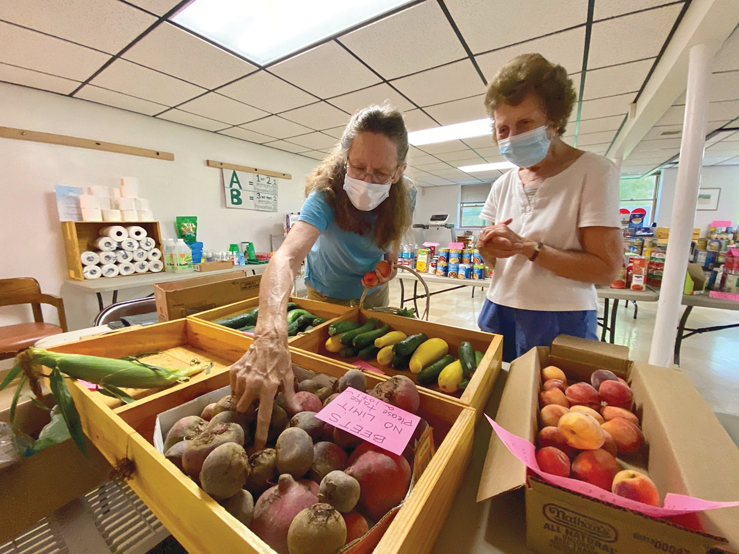 Volunteers Holly Billings (left) and Helen Pereira inspect some of the fresh local produce available back in August at the Little Compton Food Bank.