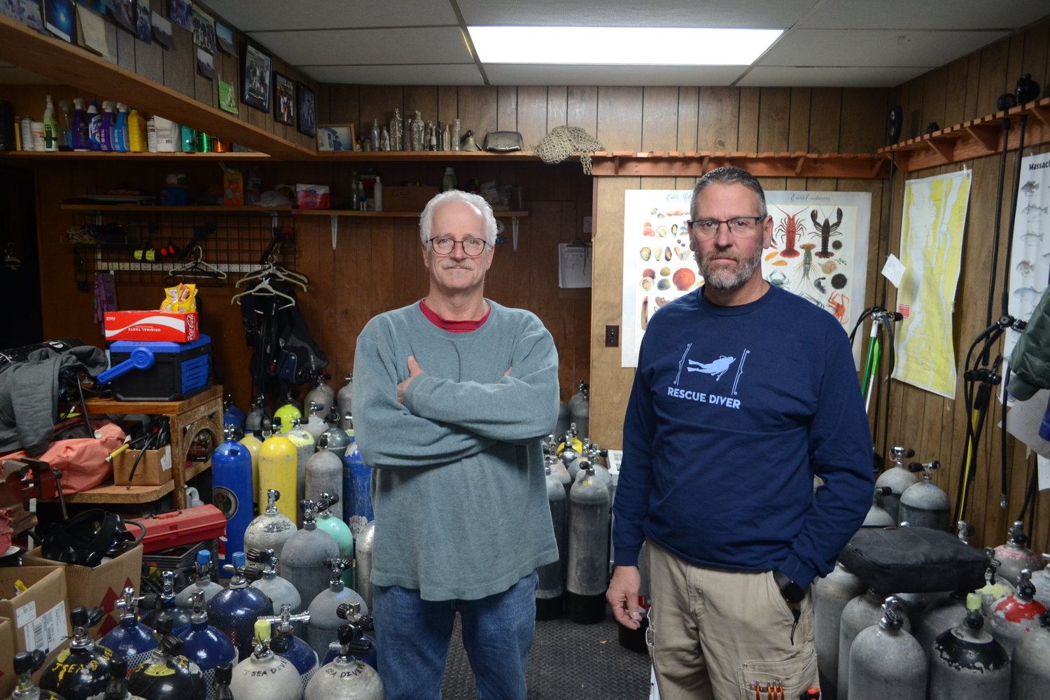 David Labrecque, founder and long-time owner of the East Bay Dive Shop, and Kevin Quinlan, who recently purchased the shop from Labrecque, inside the shop’s equipment storage area on Friday.