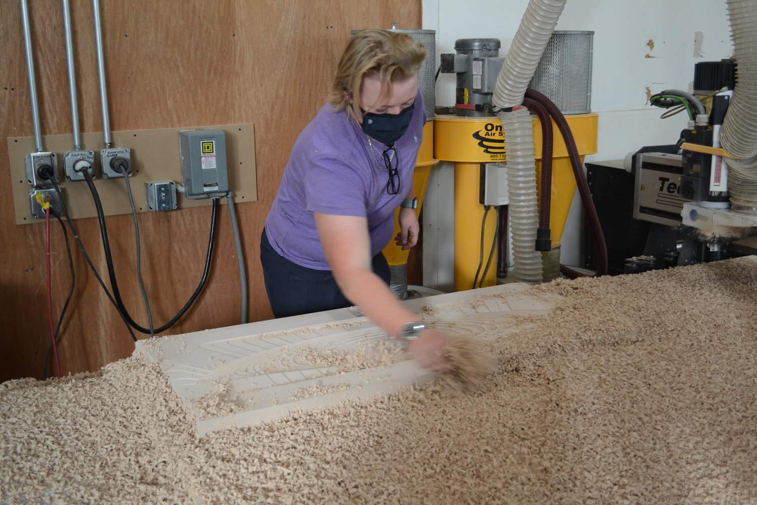 Darya Blout, founder and owner of Canapitsit Customs in Bristol, brushes shavings away from a mold as it is crafted by a CNC machine. The mold was ordered by a local kiteboarding manufacturer.