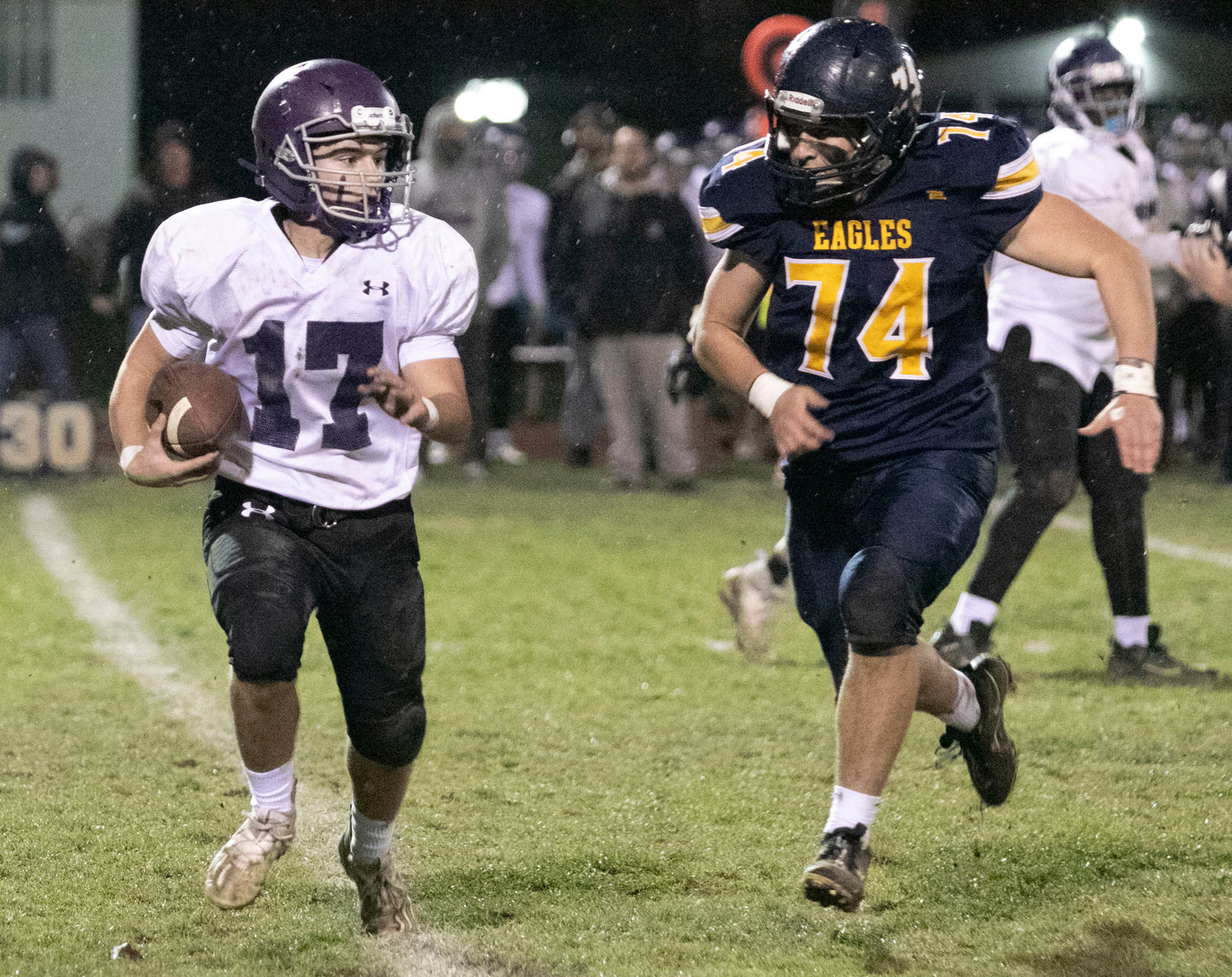 Huskies running back Riley Howland attempts to get around the end but is run down by Eagles lineman Jake Zimmerman.