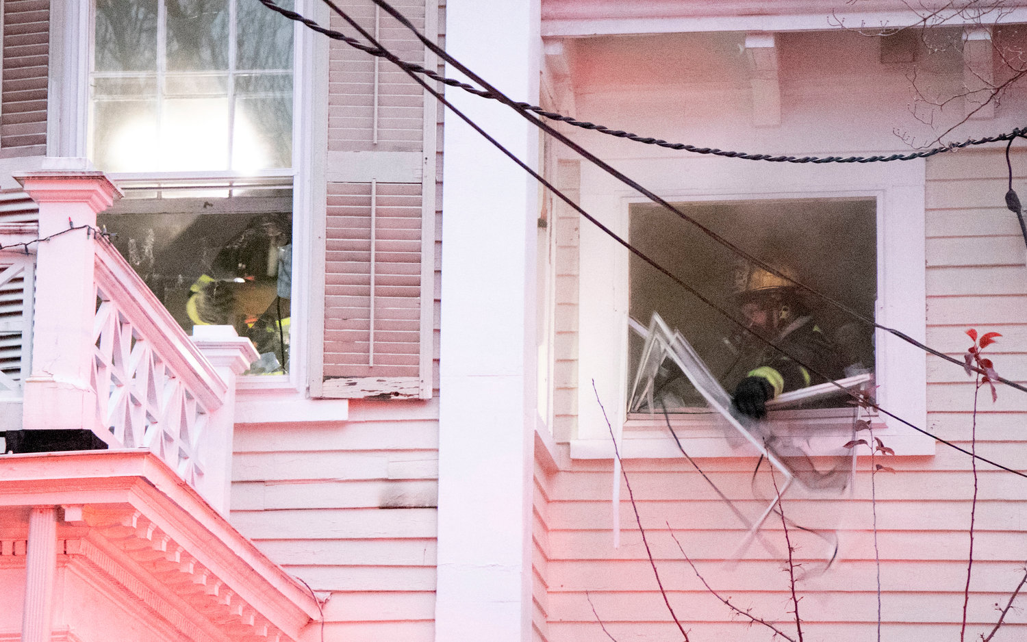 A firefighter breaks a window to let smoke out of the house as they try to find the source of the fire.