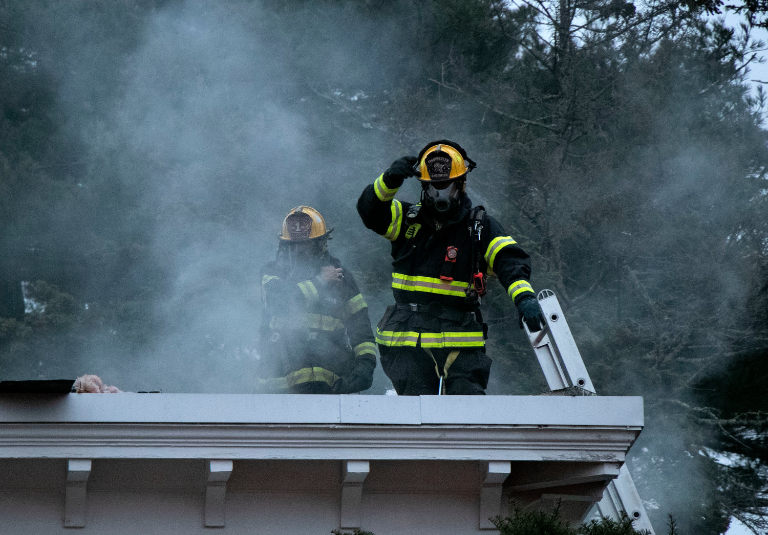 Firemen signal down to the ground after cutting a hole in the roof.