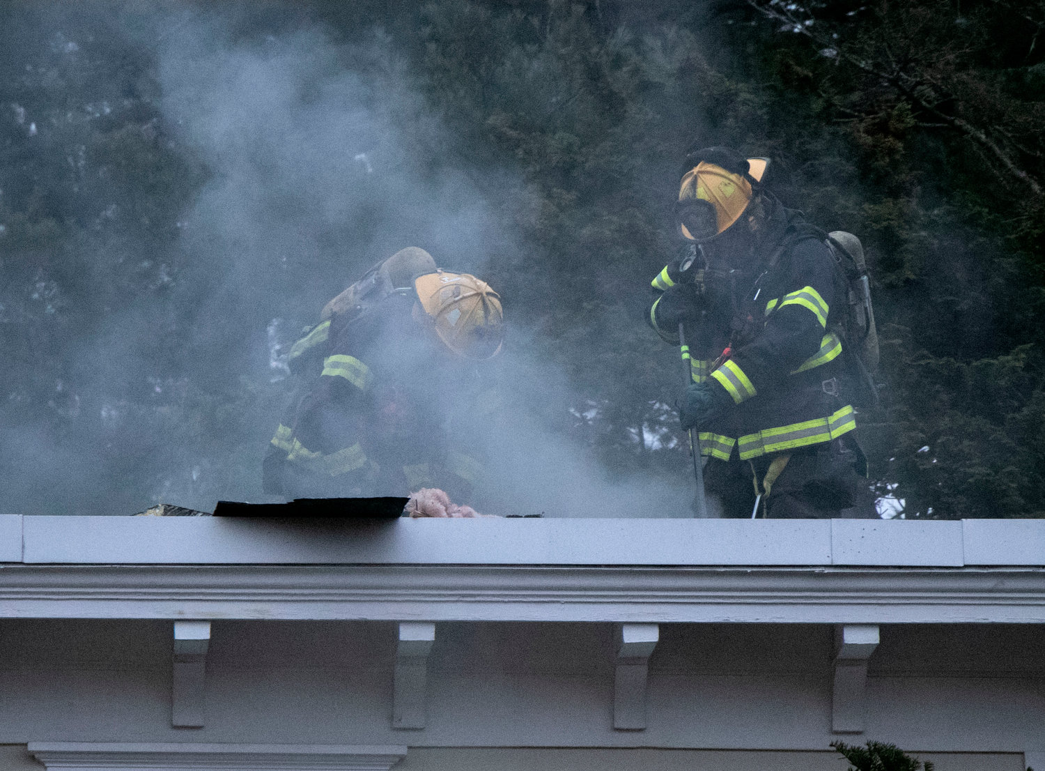 A plume of smoke rises from a hole that firefighters cut into the roof of the Alfred Drown home.