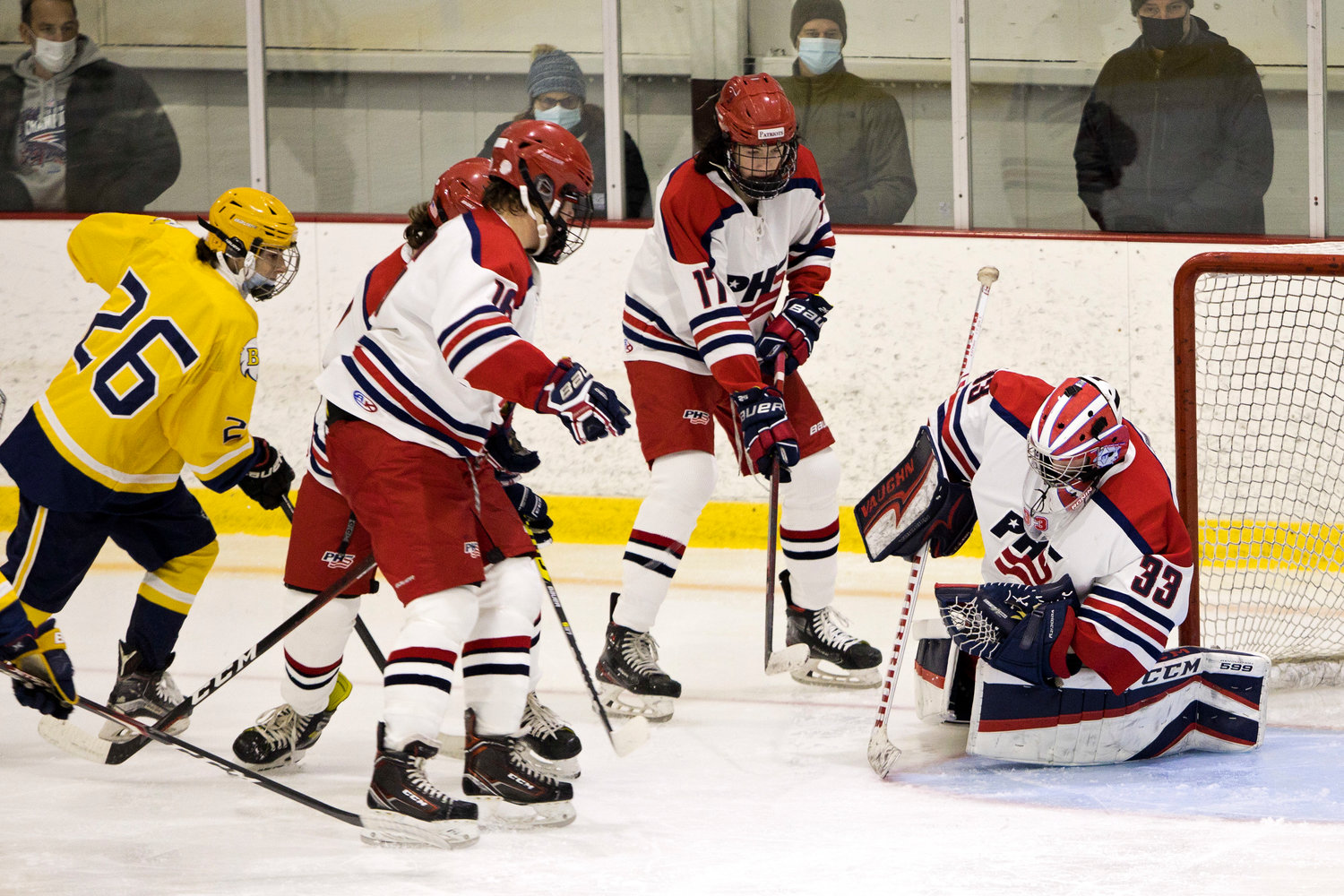 The Portsmouth defensive line protects the net, helping goalie Stephen Dutra stop a Barrington shot.