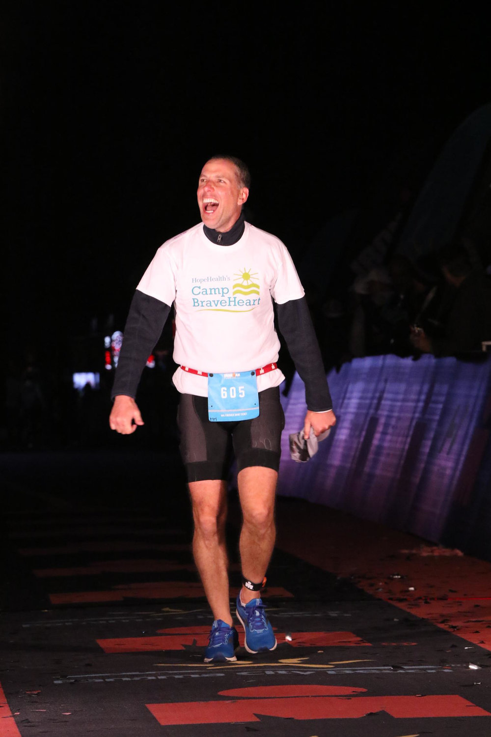 Barrington’s Mark Tracy, wearing a Camp Braveheart T-shirt, crosses the finish line at this year’s Ironman Florida. Mr. Tracy raised money for the camp, which helps children who have suffered a loss of a parent or a sibling.