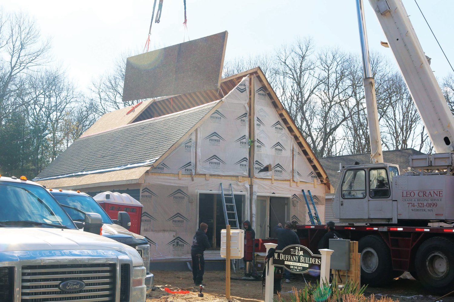 Crews assemble sections of a modular home in Falmouth, Mass.
