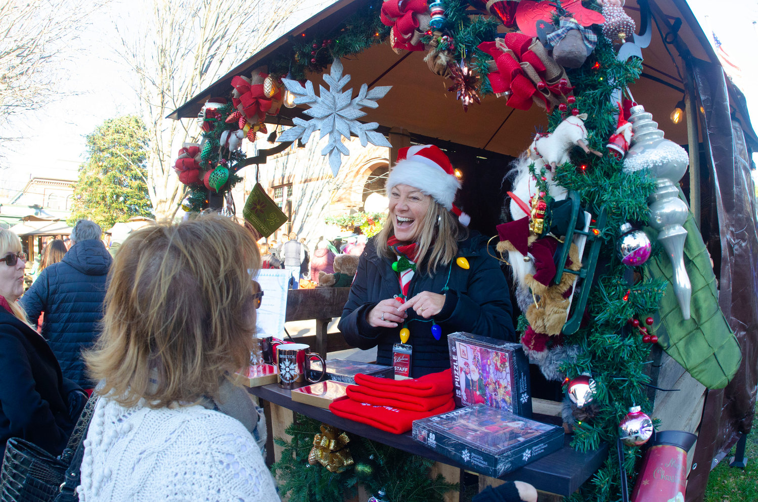 Kathleen Flaherty, in elf hat, speaks to market goers from the Christmas in Bristol committee booth.