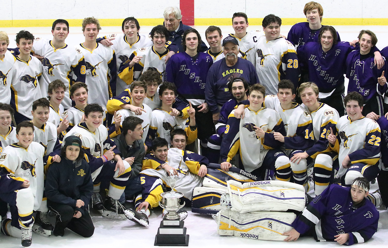 At the center of this 2020 post-game gathering of Barrington and Mt. Hope boys’ ice hockey players is J.P. Medeiros, father of the young man whose name has been memorialized with an annual hockey tournament and scholarship fund for two decades.