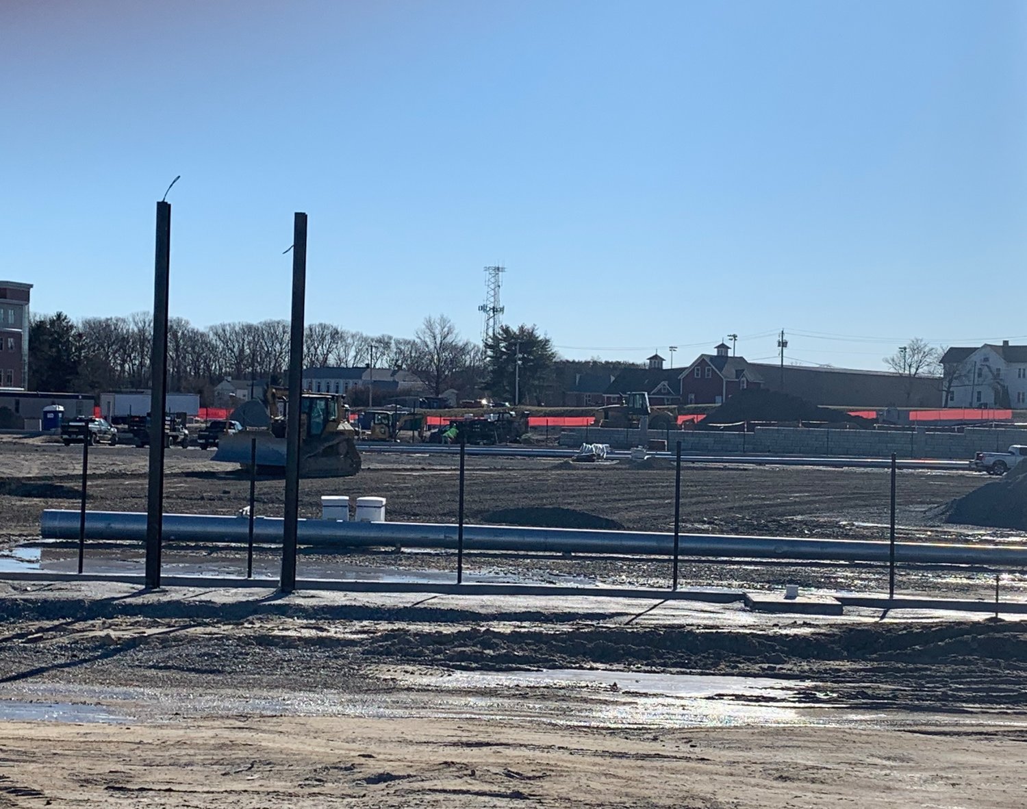 Construction crews grade the baseball field in front of the new East Providence High School on Tuesday, Jan. 4, while a light pole and the scoreboard frame await installation.