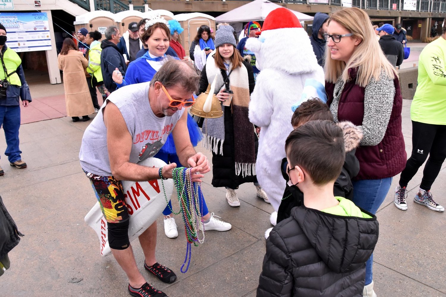 Bryan Ganley passes out Mardi Gras beads to young spectators, including Wish Child Benjamin and his Mom and brother, on Easton’s Beach at Saturday’s New Year’s Day event.