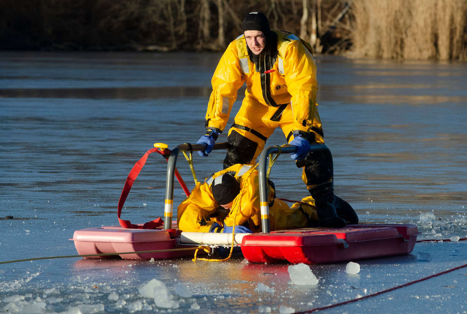 Barrington firefighter Pat Reihl pulls probationary firefighter Jared Pedro from the icy water at Brickyard Pond during an ice rescue training session on Friday afternoon. The firefighters used a special sled that disperses their weight to create better stability and also transitions from water to ice.