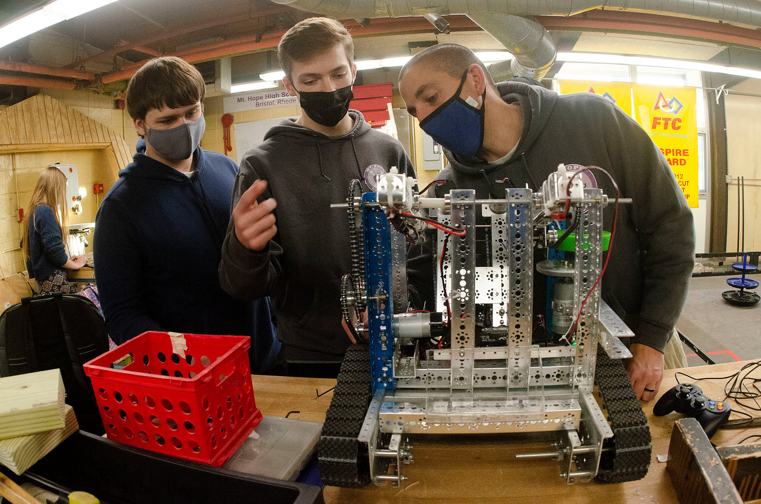 Bryan Conway (left) Simon Thibault and teacher Ryan Garrity work on their team's robot.