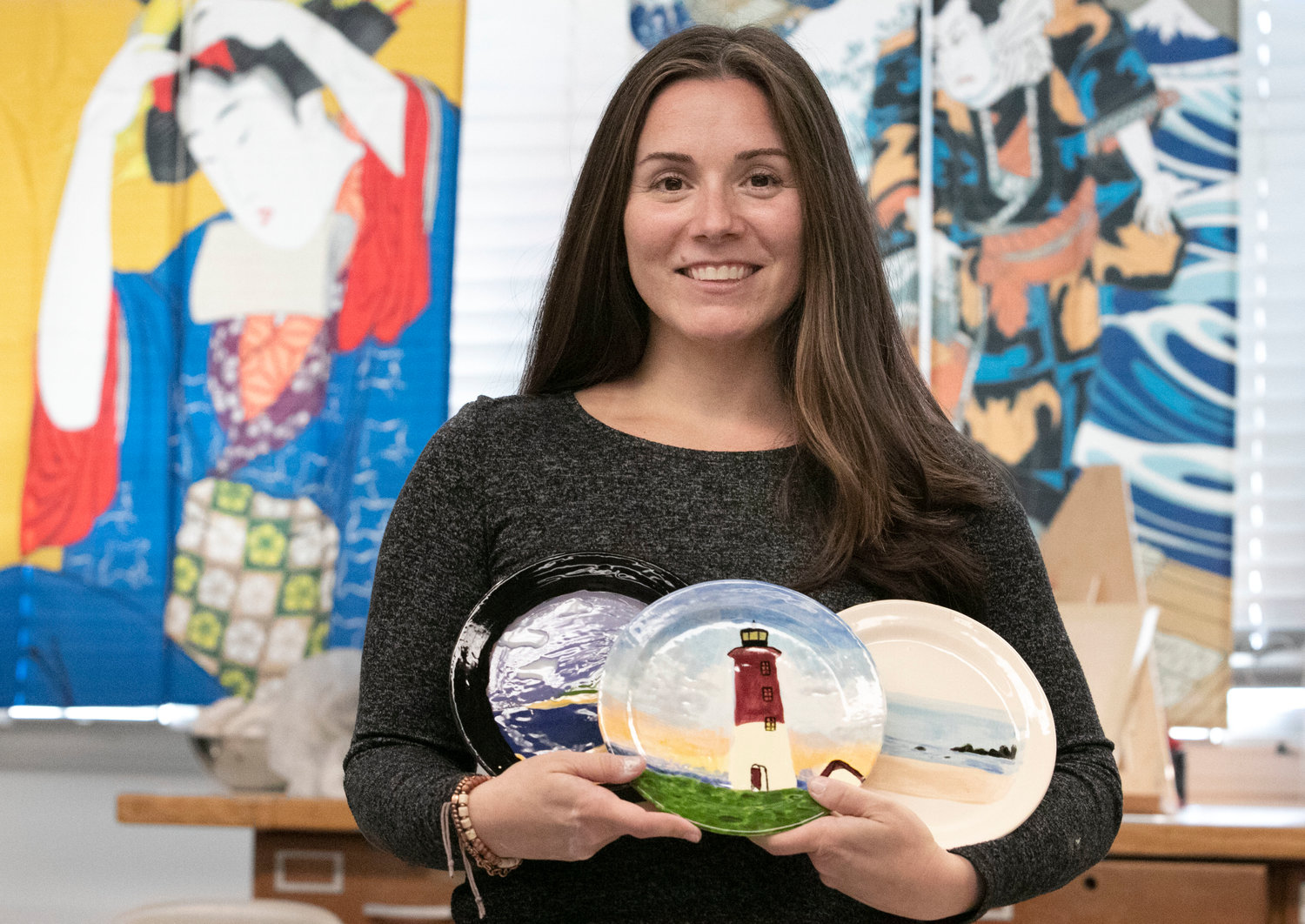 Ceramics and art teacher Eileen Locicero holds up works made by her students.
