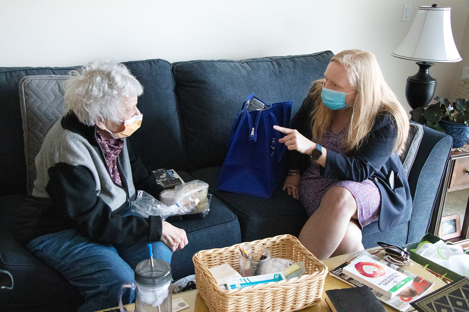 Helen Spets (left), a 95-year-old resident of Bay View Estates, chats with R.I. Meals on Wheels Executive Director Meghan Grady during a visit to her apartment on March 15. Town Council Vice President Linda Ujifusa also helped deliver a meal of shepherd’s pie, plus a blanket, slippers and a puzzle.