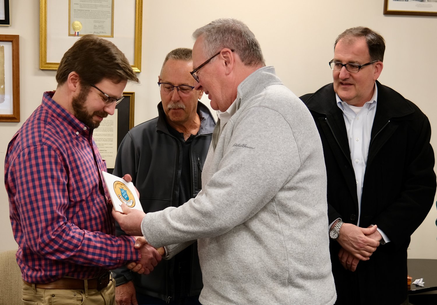 Outgoing Assistant Planner Mike Asciola (left) receives a town tile from Town Administrator Richard Rainer, Jr. during a going-away party in his honor at Town Hall last Thursday. Behind them are Zoning Board of Review Chairman Jim Nott (left) and Planning Board Chairman Edward Lopes, Jr.
