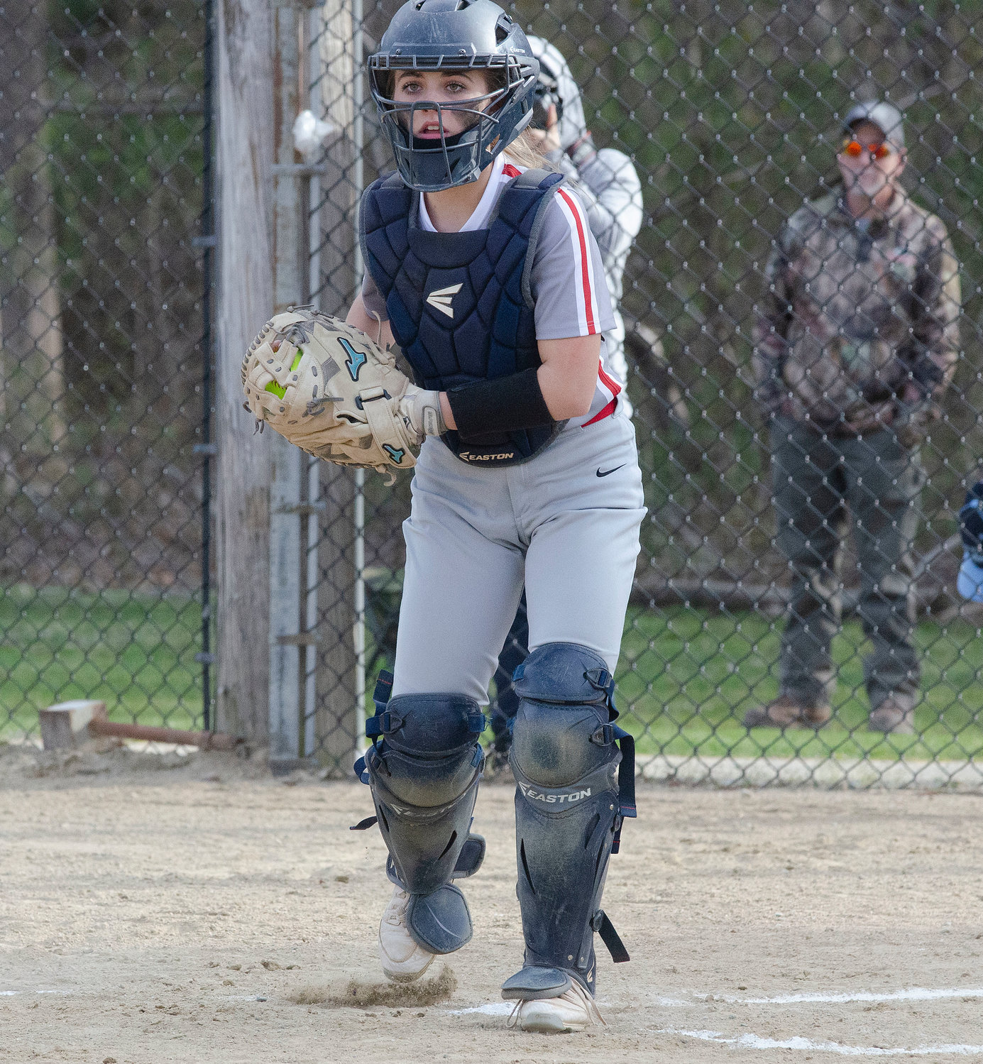 Catcher Ava Mendence looks back a runner after fielding a throw to home plate.
