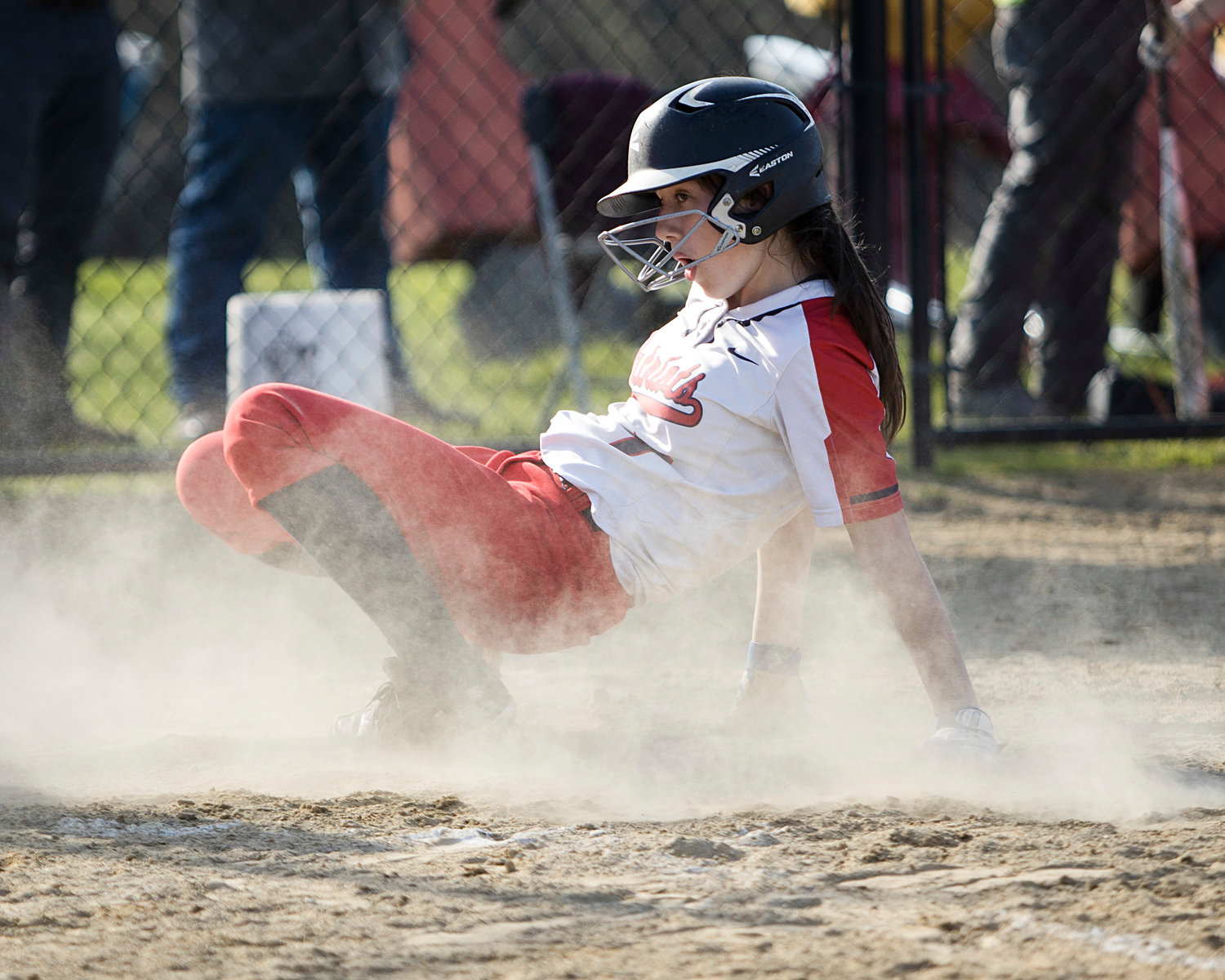 Ella Daly looks for the call as she slides into home plate, scoring the first run for the Patriots.