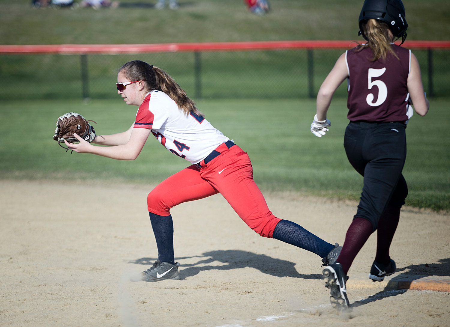 Kaelyn Mahoney attempts to make a play at first as a Tiverton runner reaches the bag.