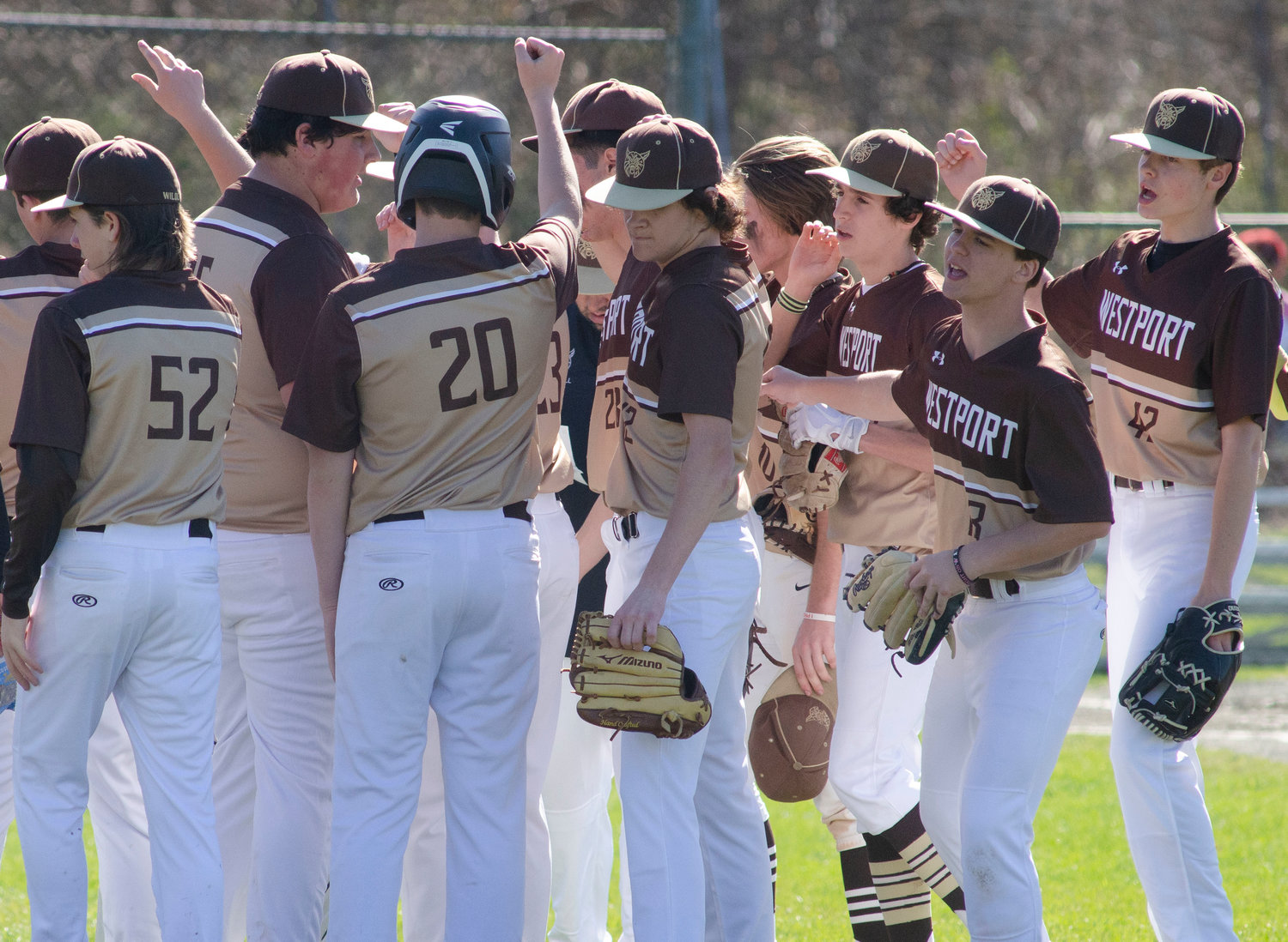 Cam Leary (middle) and the team huddle in front of the dug out after an inning in the field.