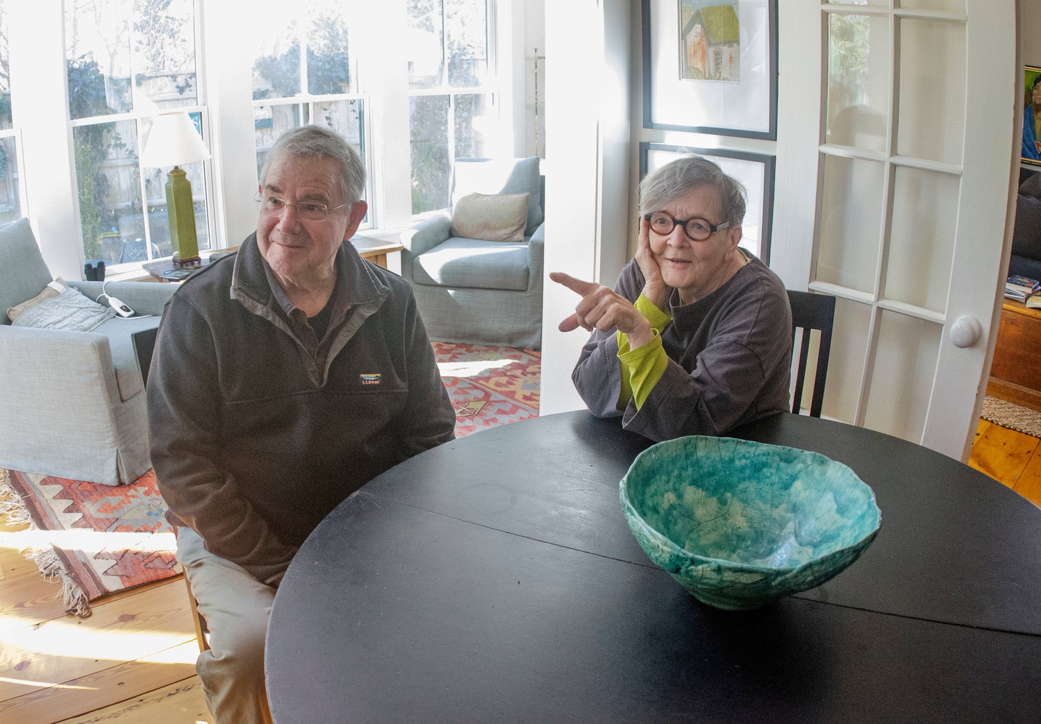 Mitch and Jane Henderson relax inside their 262-year-old home. Jane, the artist, has helped decorate with original artwork, including her own pottery, and Mitch, the engineer, helped sketch out a solar energy plan that may pay for itself in a decade.