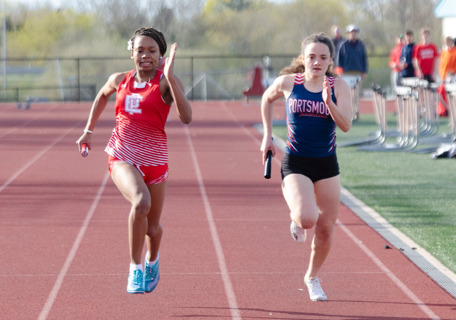 Fourth-leg sprinters Nazarae Phillip of East Providence (left) and Portsmouth's Elly Skeels run toward the finish line in the 4x100-meter relay.
