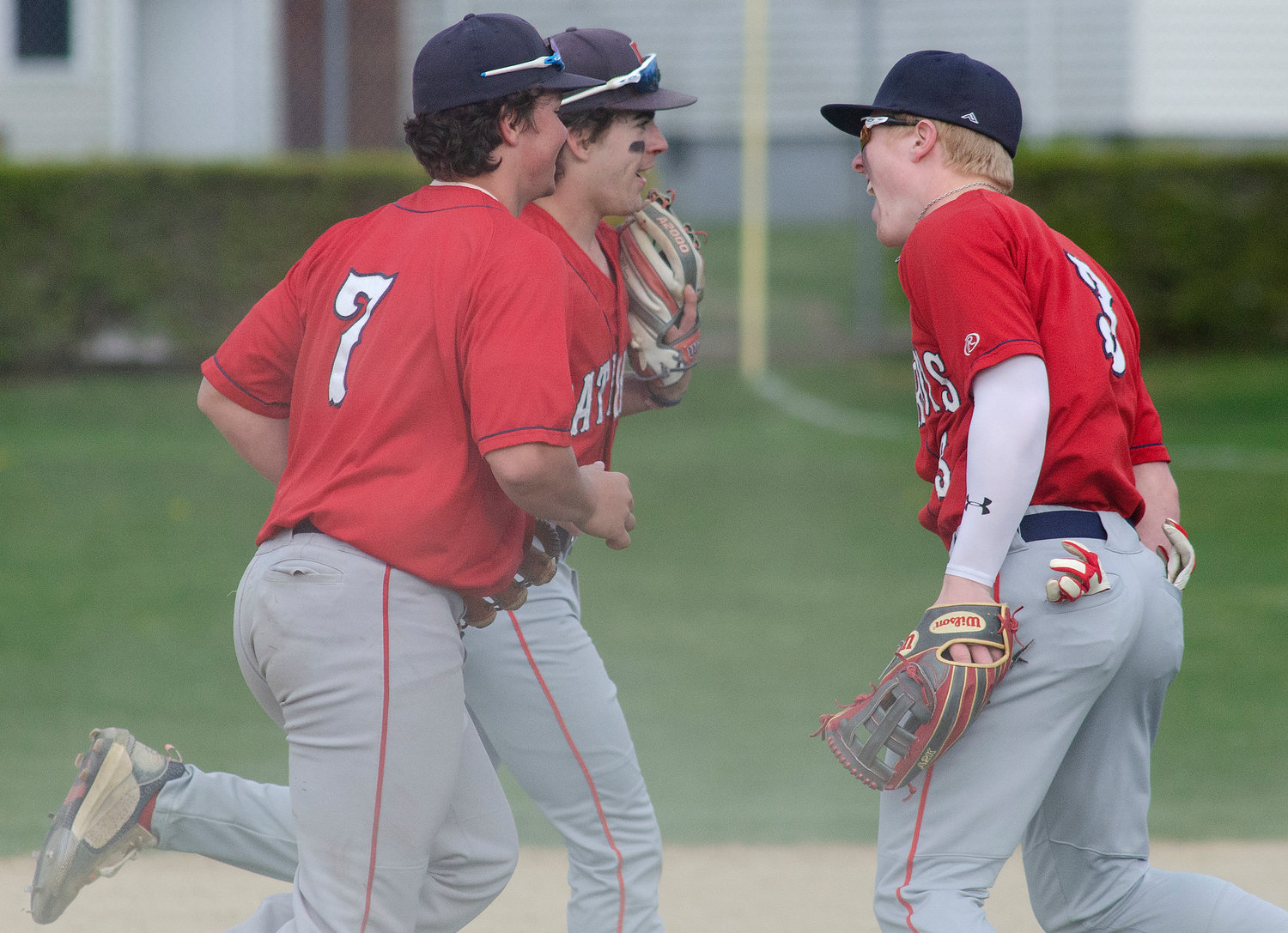 Gavin Bicho (right) celebrates with outfielders Shane Harvey (left) and Nick Spaner (middle) after they made big plays to get the Patriots out of an inning last week.
