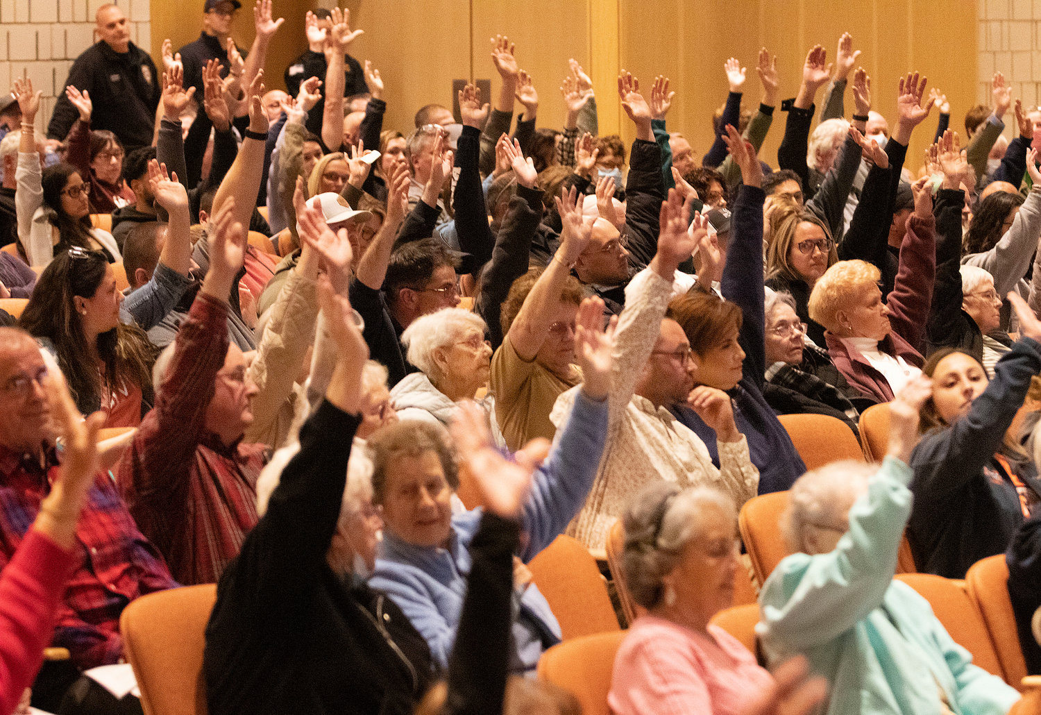 Voters raise their hands to vote in favor of helping to fund the new Diman School project in Fall River. 