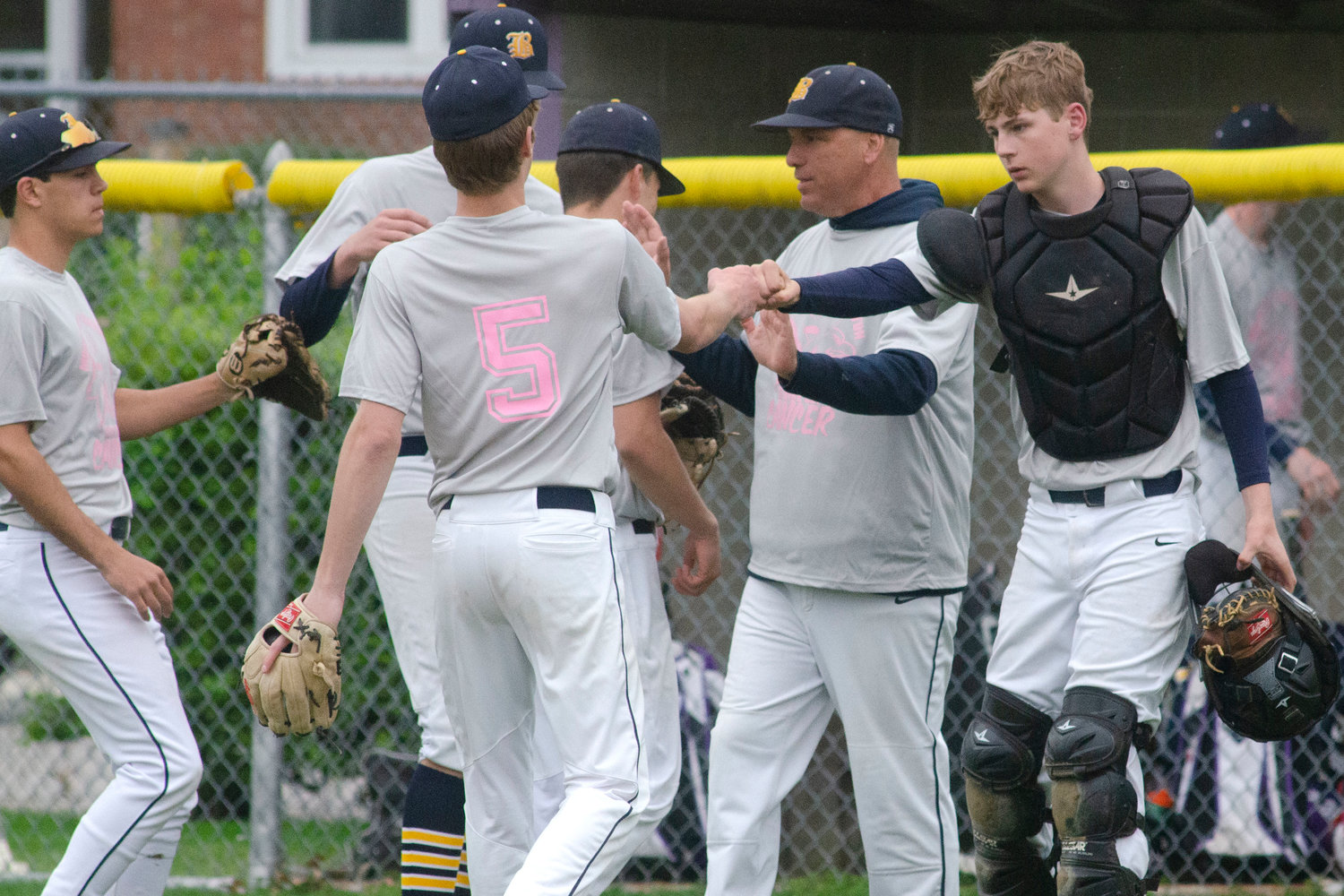 Barrington High School Baseball Coach Vin Scandura and catcher Evan Anderson fist-bump teammates as they run off the field after a clean inning against the Huskies on Friday. The two teams played a special benefit baseball game to raise money for Jimmy Fund.