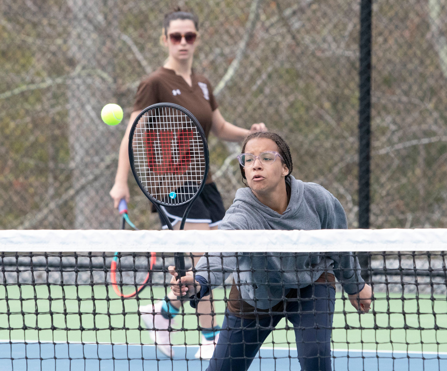 Taliyah Raiche pokes the ball over the net for a winner with teammate Mikhaela Rego (back) looking on during their match against Diman’s Sadie Krauzyk and Sabrina Angeli. The pair fell in straight sets 5-7, 6-7(3-7).