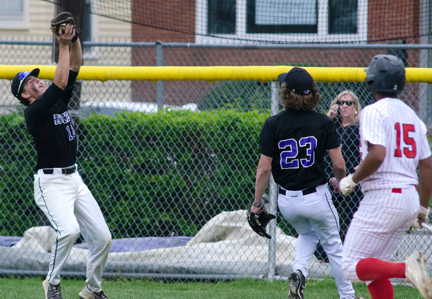 First baseman Matt Gale catches a fly ball in foul territory for an out, with pitcher Brad Denson looking on.