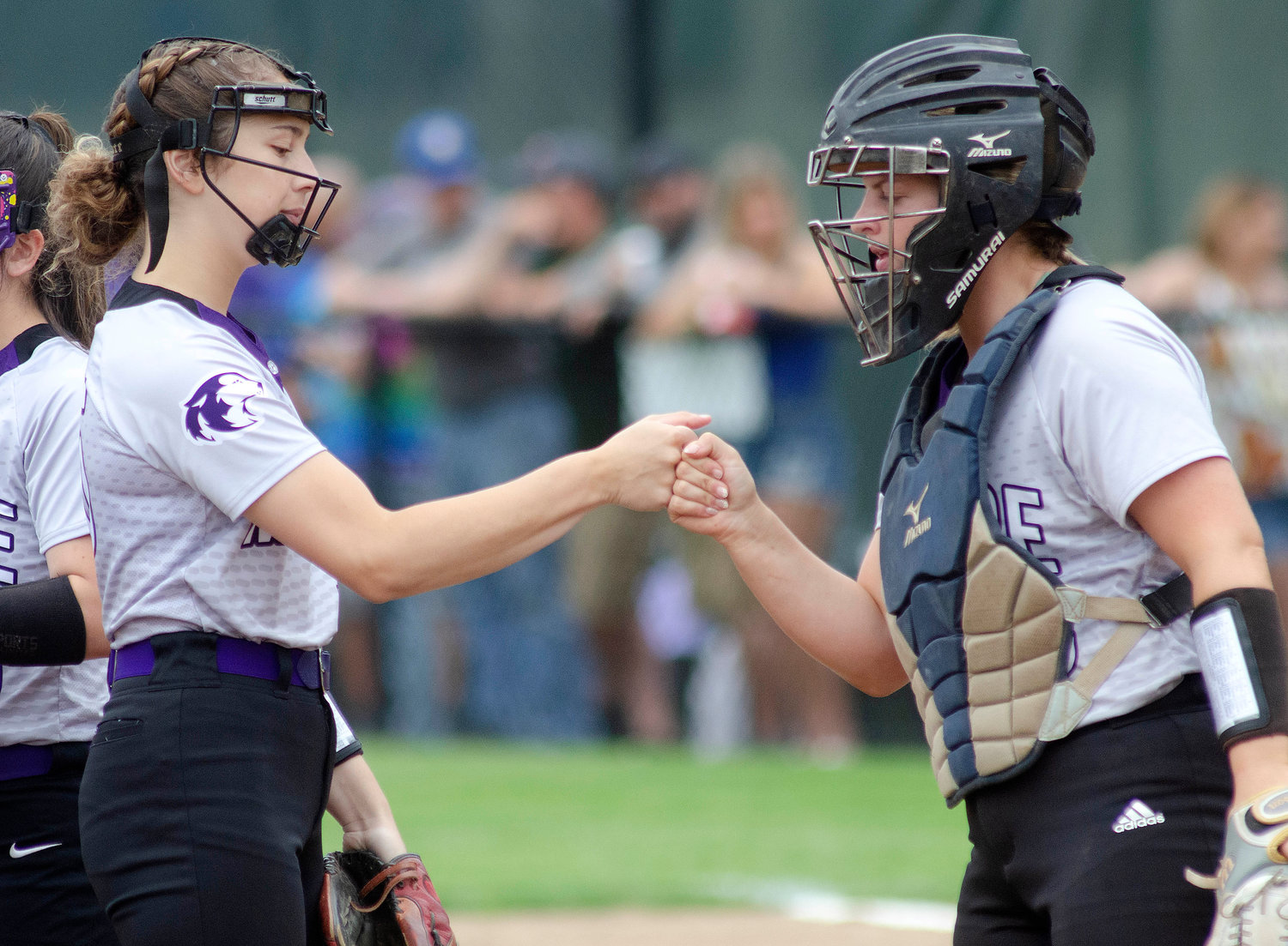 Battery mates Reily Amaral (left) and Grace Stephenson bump fists as is their custom before every inning.