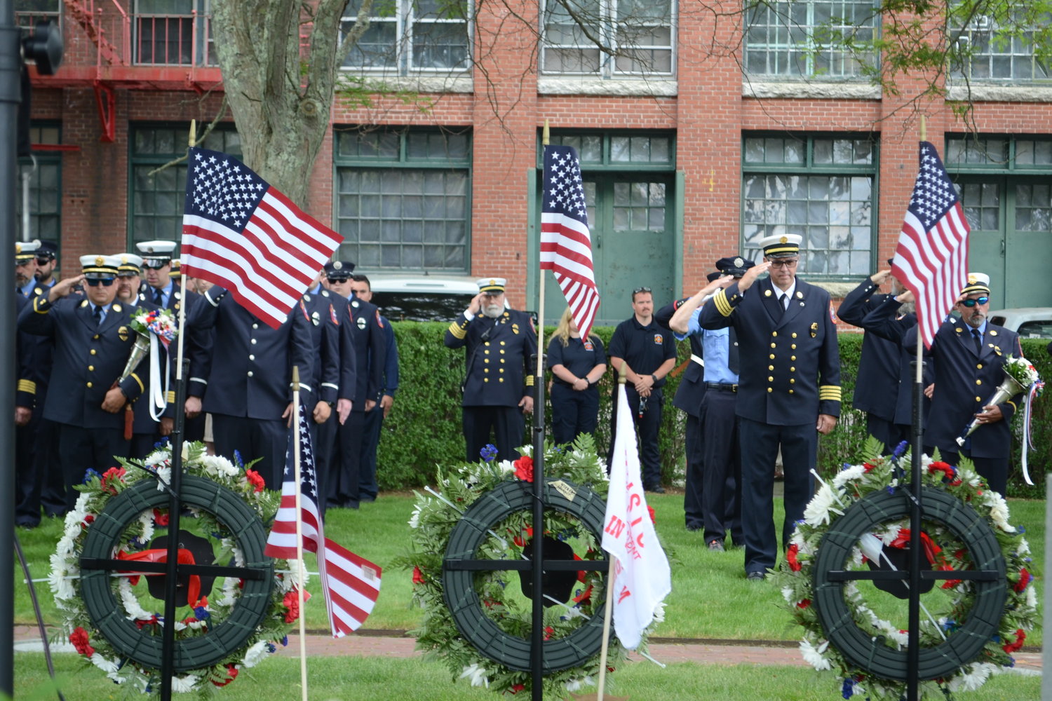 Firefighters salute during the wreath dedication ceremony at Firemen’s Memorial Park on Sunday.