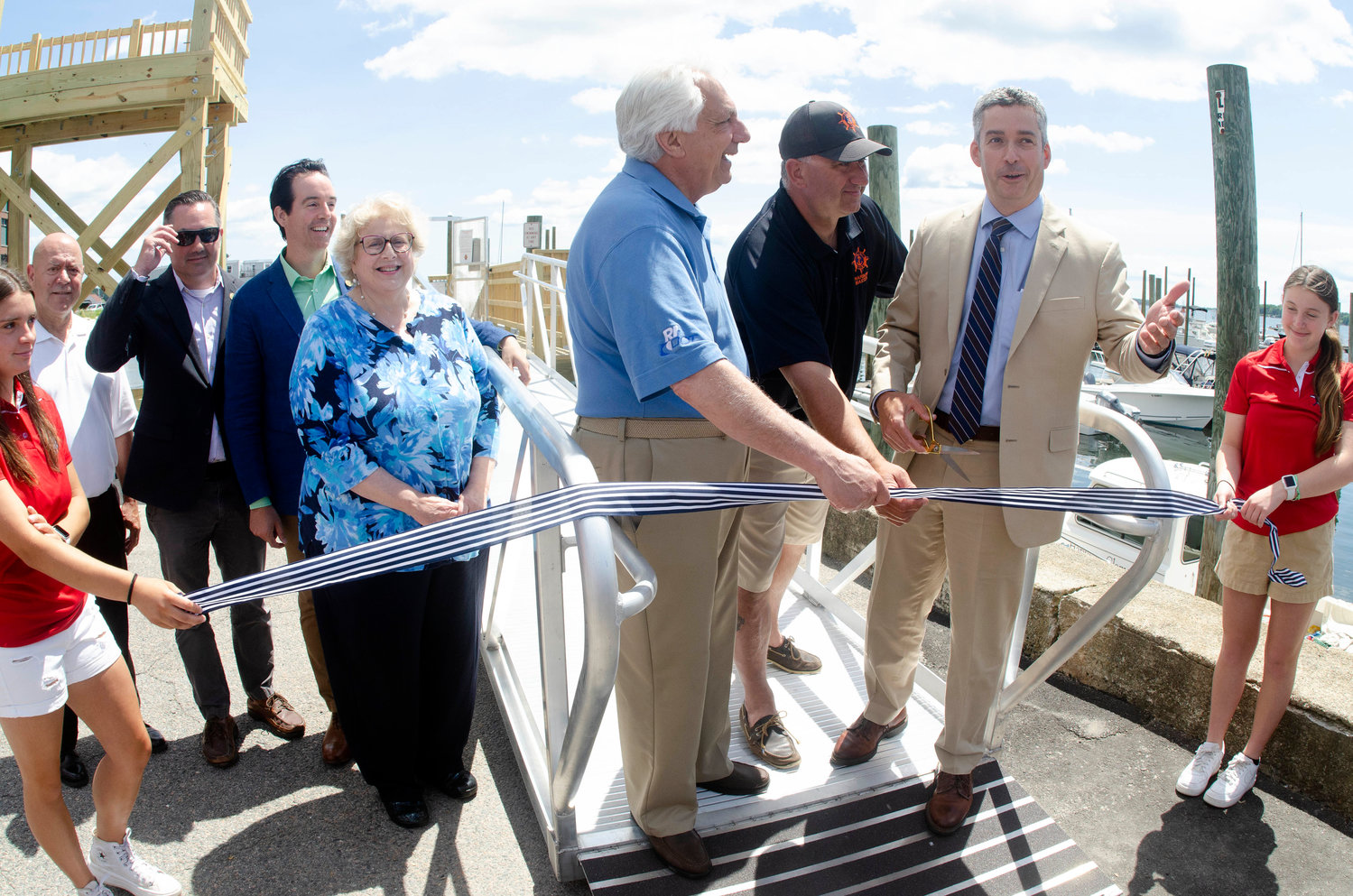 Bristol marina employees hold onto the ribbon as town councilors Tony Teixeira, Aaron Ley, Tim Sweeney, Mary Parella look on as DOT director Peter Alviti Jr., harbormaster Gregg Marsili and town administrator Steve Contente cut the ribbon to open the new dock.