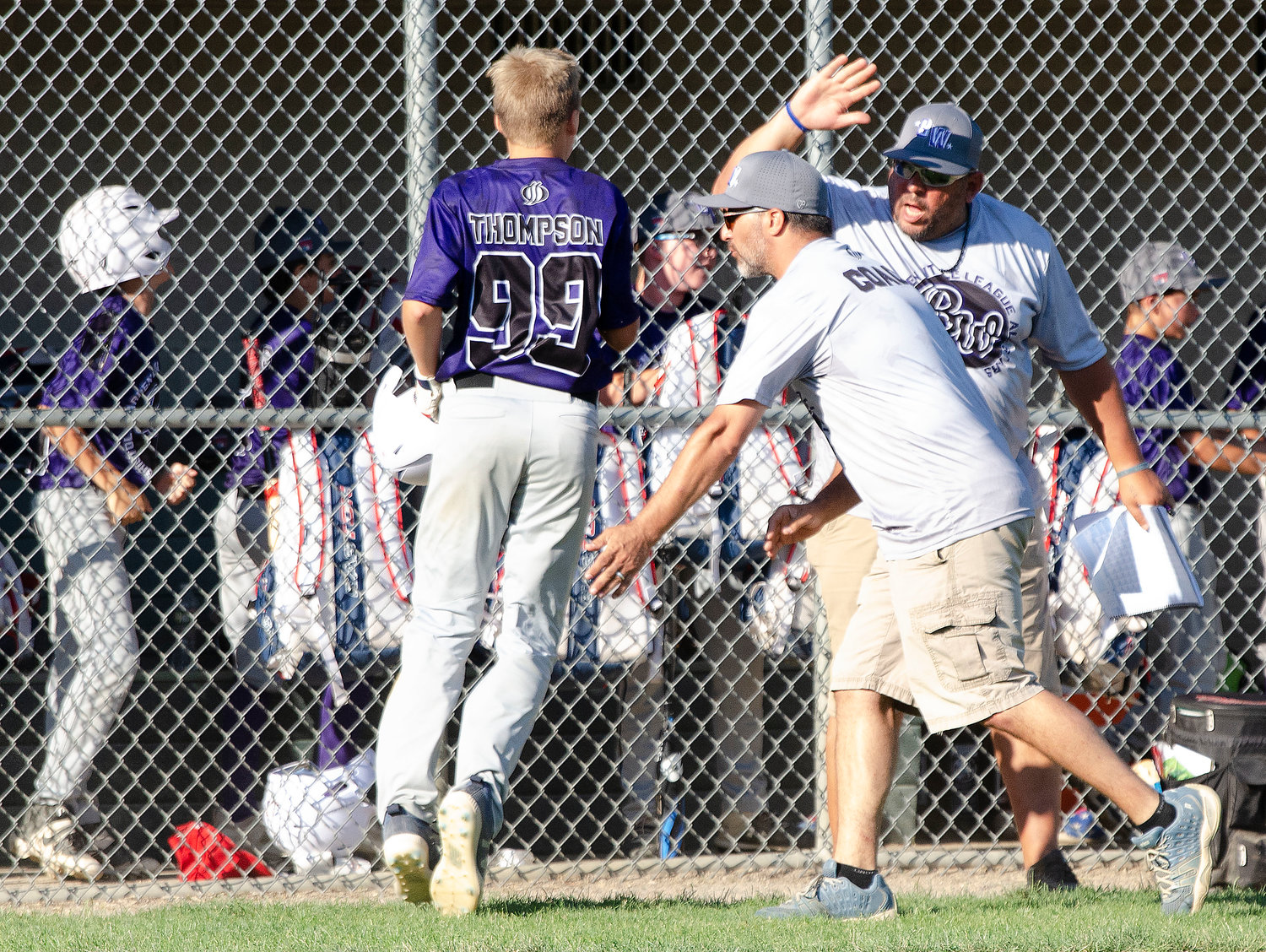 Ryan Thompson (left) celebrates after scoring the second run in the second inning with coach Steve Furtado (right) and another coach.
