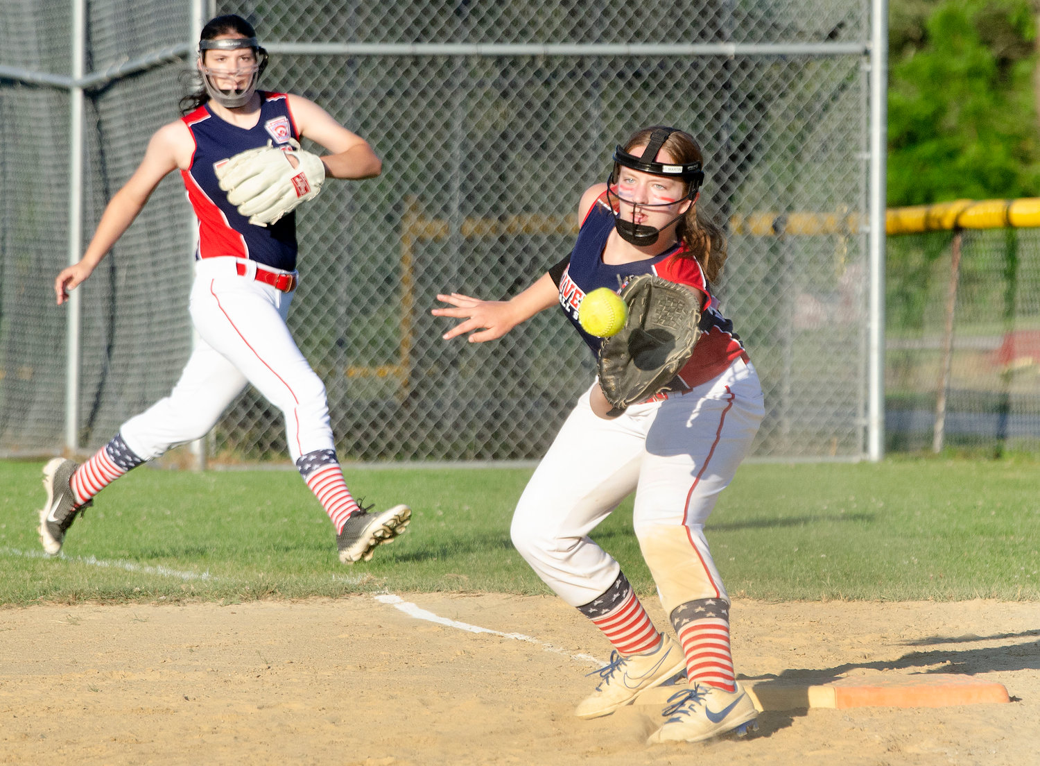 Right fielder Isabella Halstead (left) backs up first baseman Carlie Martin as she takes a throw from third baseman Paisley Parisee to record an out.