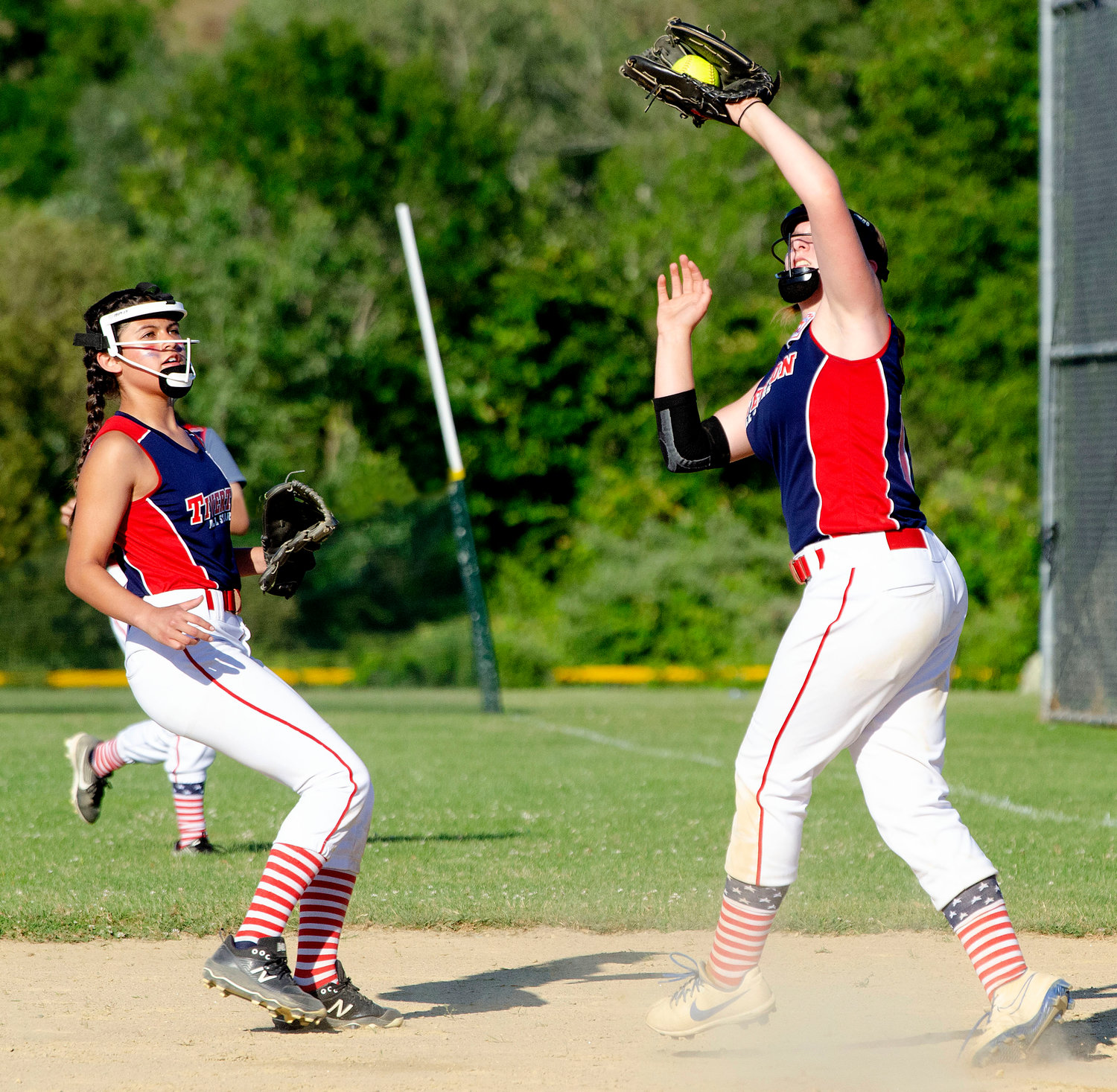 Second baseman Sophia Morales (left) looks on as first baseman Carlie Martin (right) snags a pop fly in the first inning.